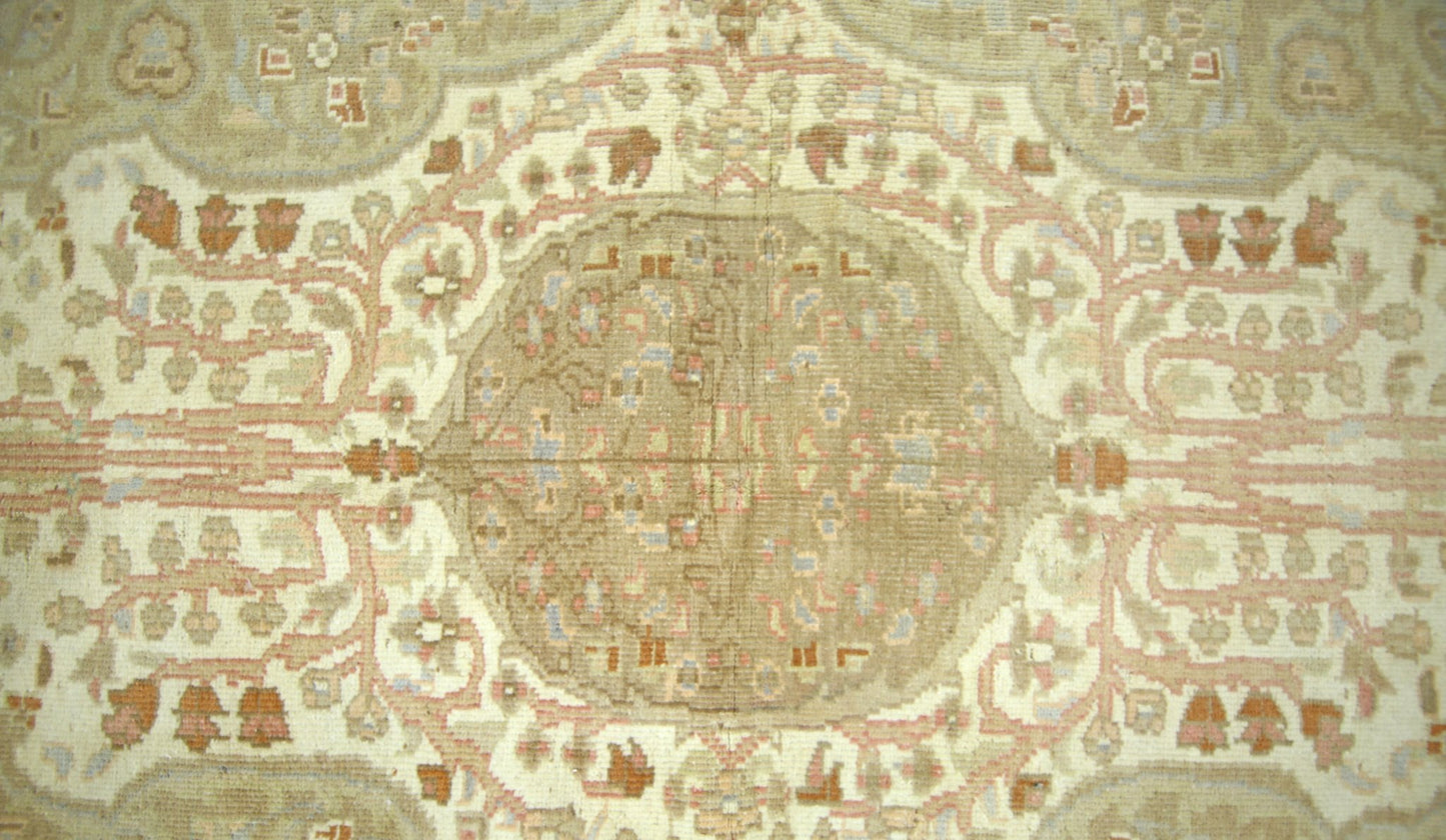 A vintage Pakistani rug featuring a central medallion with intricate floral patterns in muted tones.