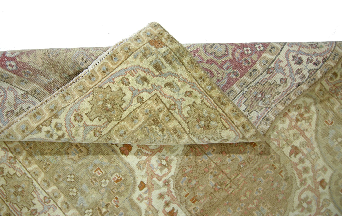 A folded vintage Pakistani rug featuring a traditional geometric pattern in muted earth tones.