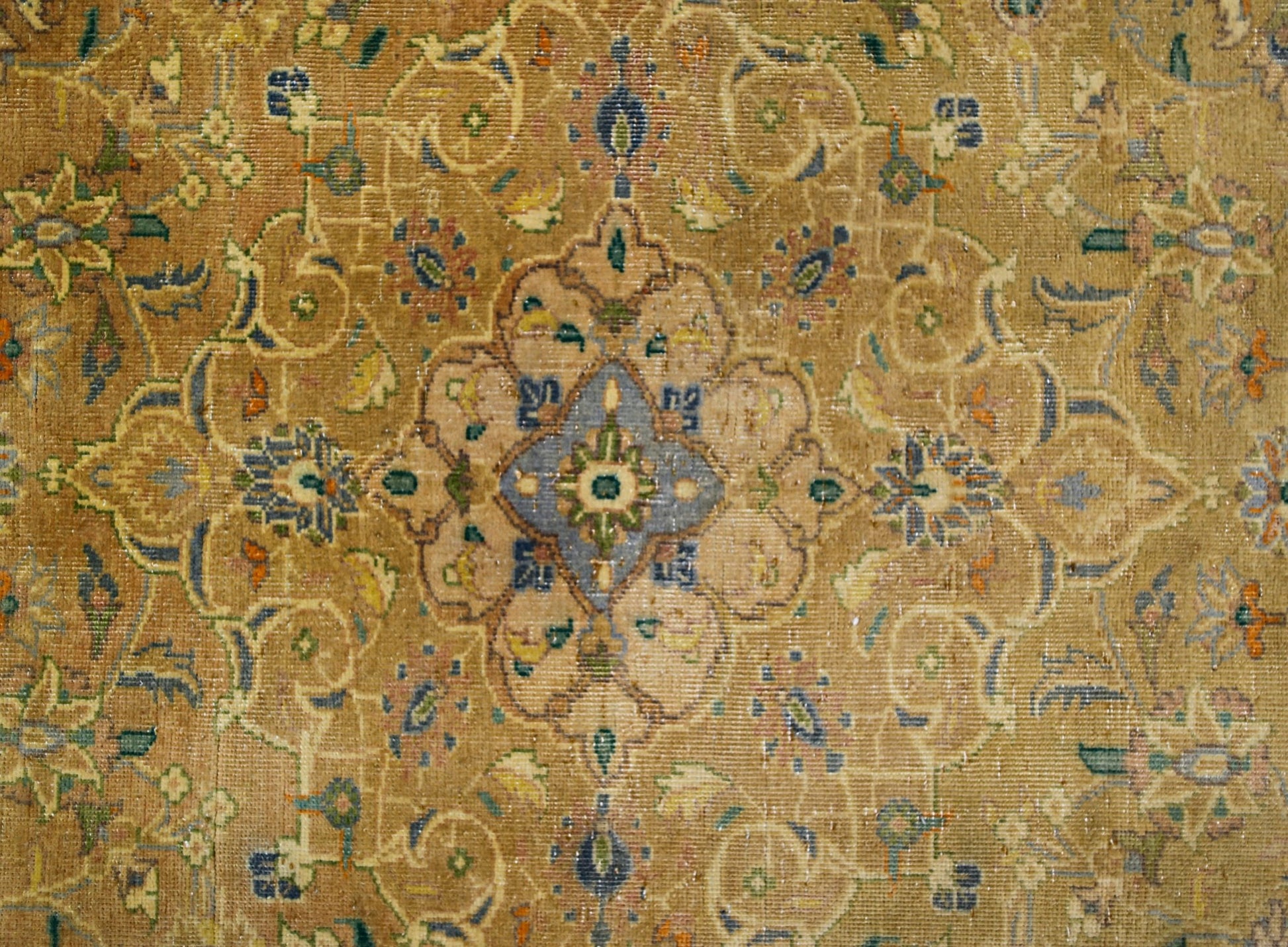 A vintage rug featuring an intricate floral medallion design in soft, muted earth tones.
