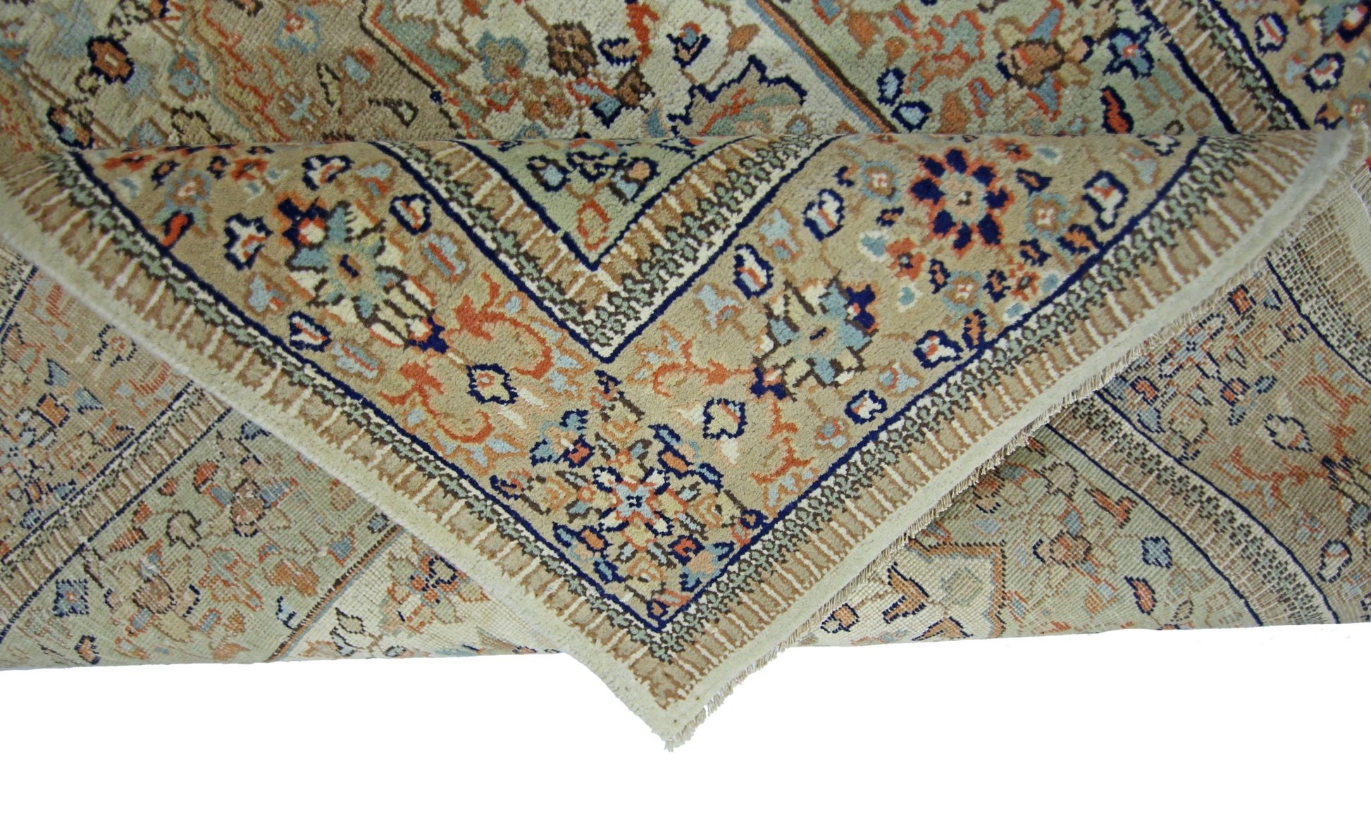 A folded vintage Pakistani wool rug featuring a traditional floral pattern in beige, blue, and orange.