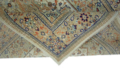 A folded vintage Pakistani wool rug featuring a traditional floral pattern in beige, blue, and orange.