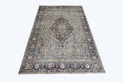 A vintage Pakistani rug featuring an intricate central medallion and floral patterns in blue and cream.