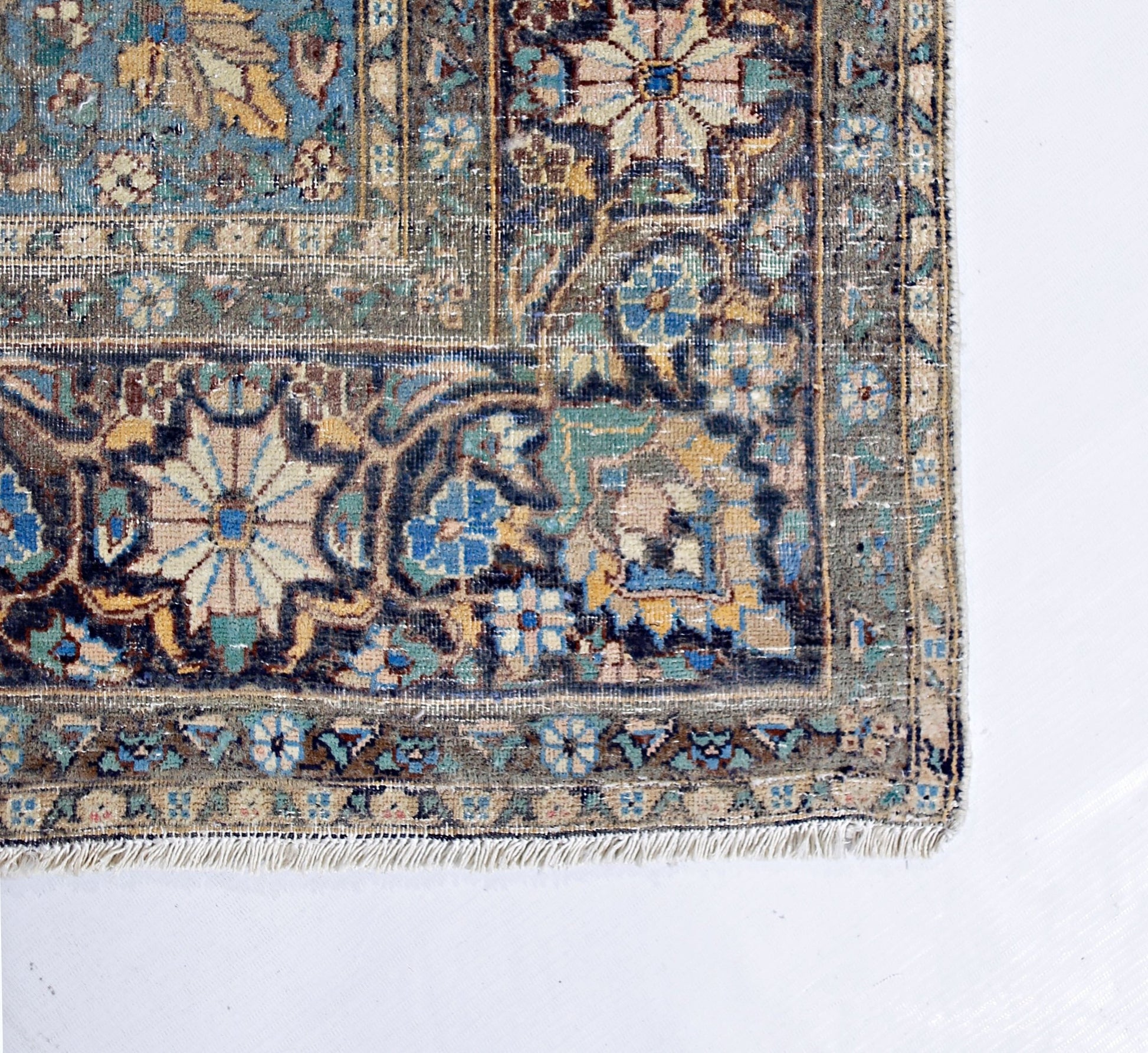 A vintage hand-knotted rug featuring an intricate floral medallion design in muted blue and tan.