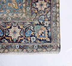 A vintage hand-knotted rug featuring an intricate floral medallion design in muted blue and tan.