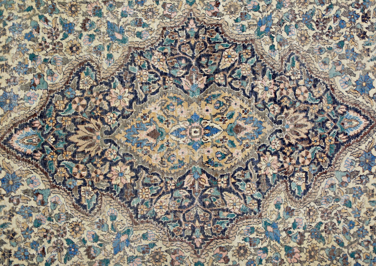 A vintage rug featuring an intricate central medallion with floral patterns in blue and gold tones.