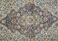 A vintage rug featuring an intricate central medallion with floral patterns in blue and gold tones.