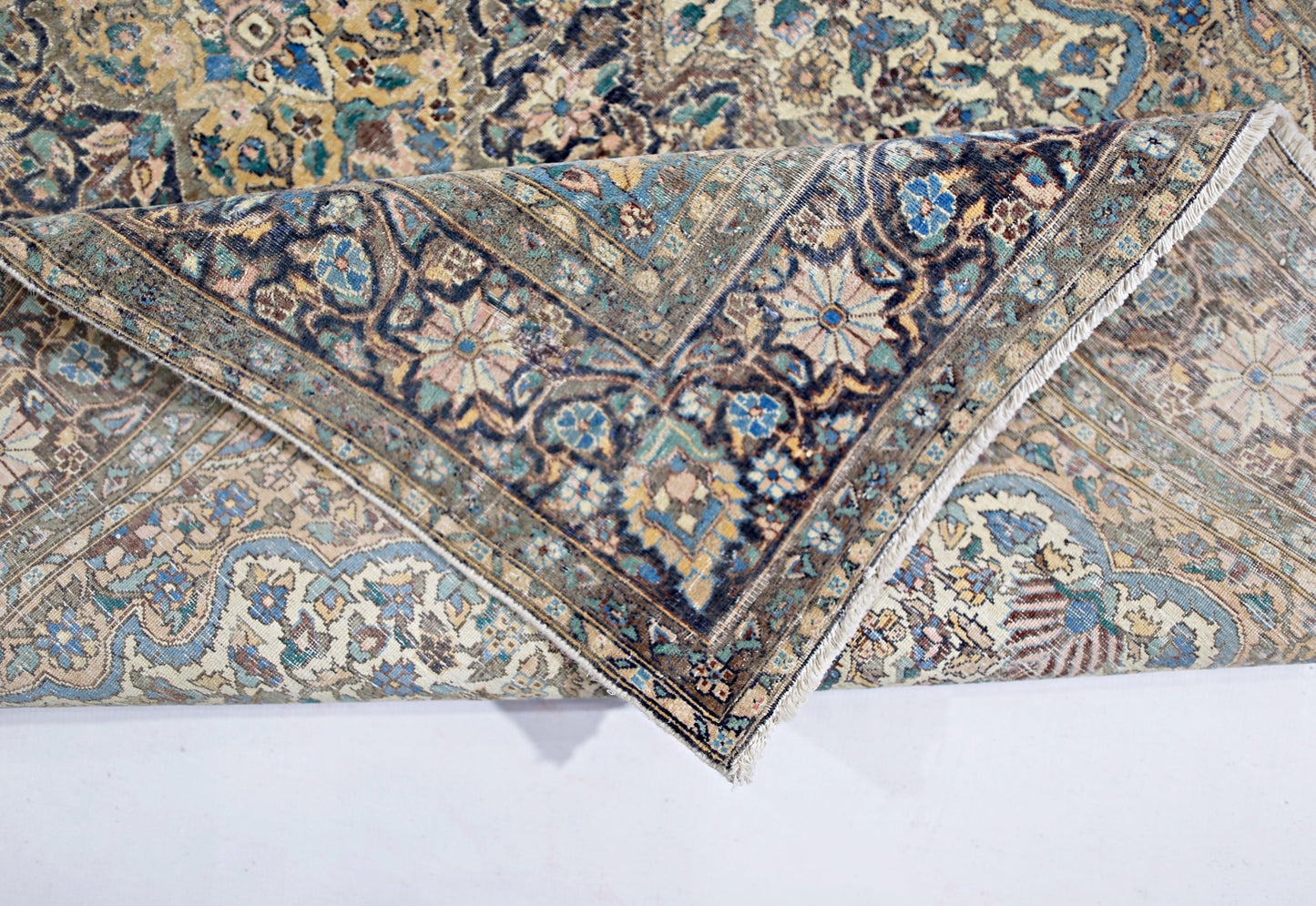 A vintage hand-knotted rug featuring an intricate floral medallion design in muted blue and gold.