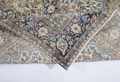 A vintage hand-knotted rug featuring an intricate floral medallion design in muted blue and gold.
