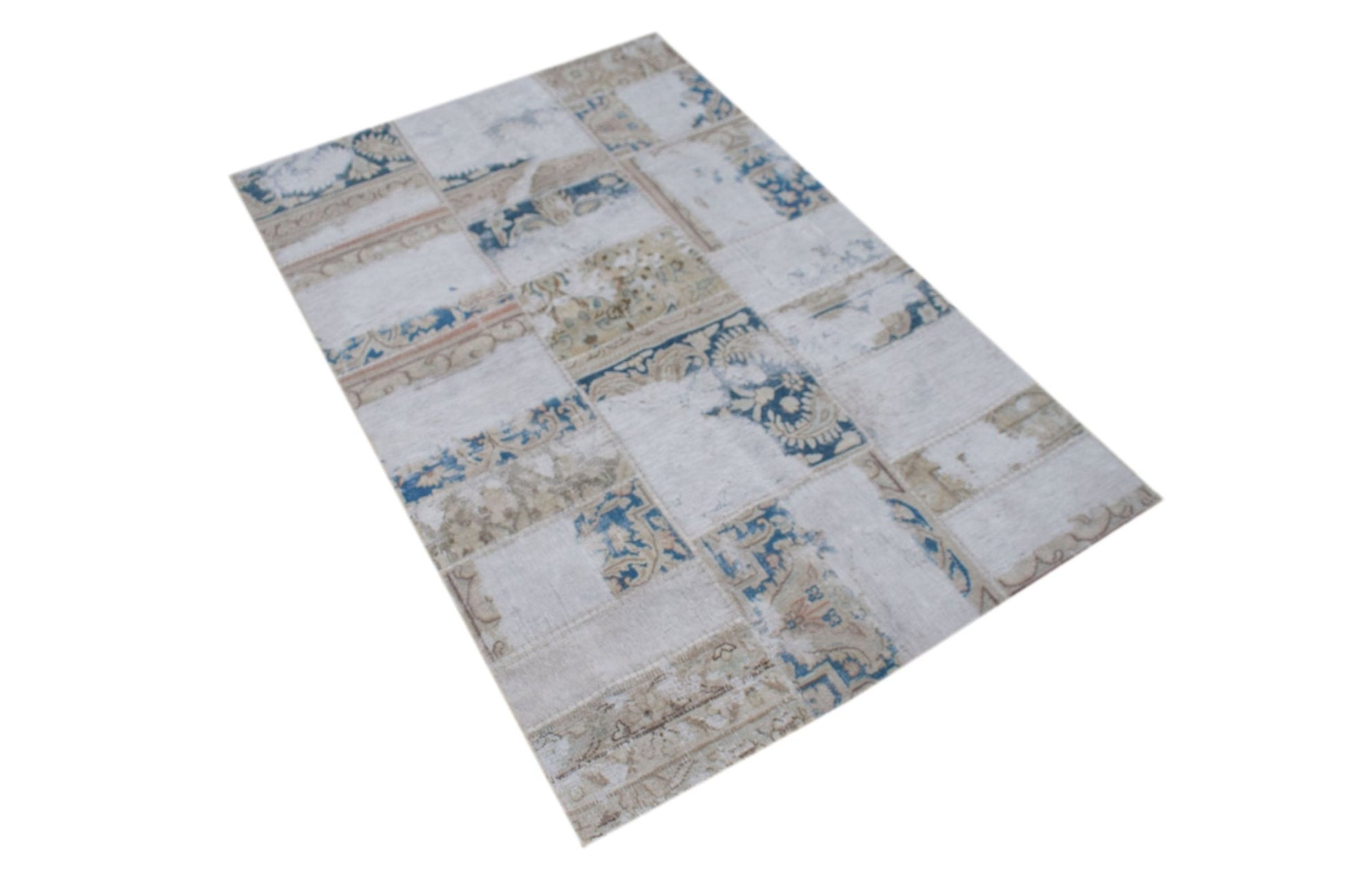 A rectangular handmade rug featuring a vintage patchwork design in shades of blue, beige, and cream.