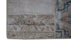 A close-up of a handmade vintage patchwork rug featuring faded blue and beige floral patterns.