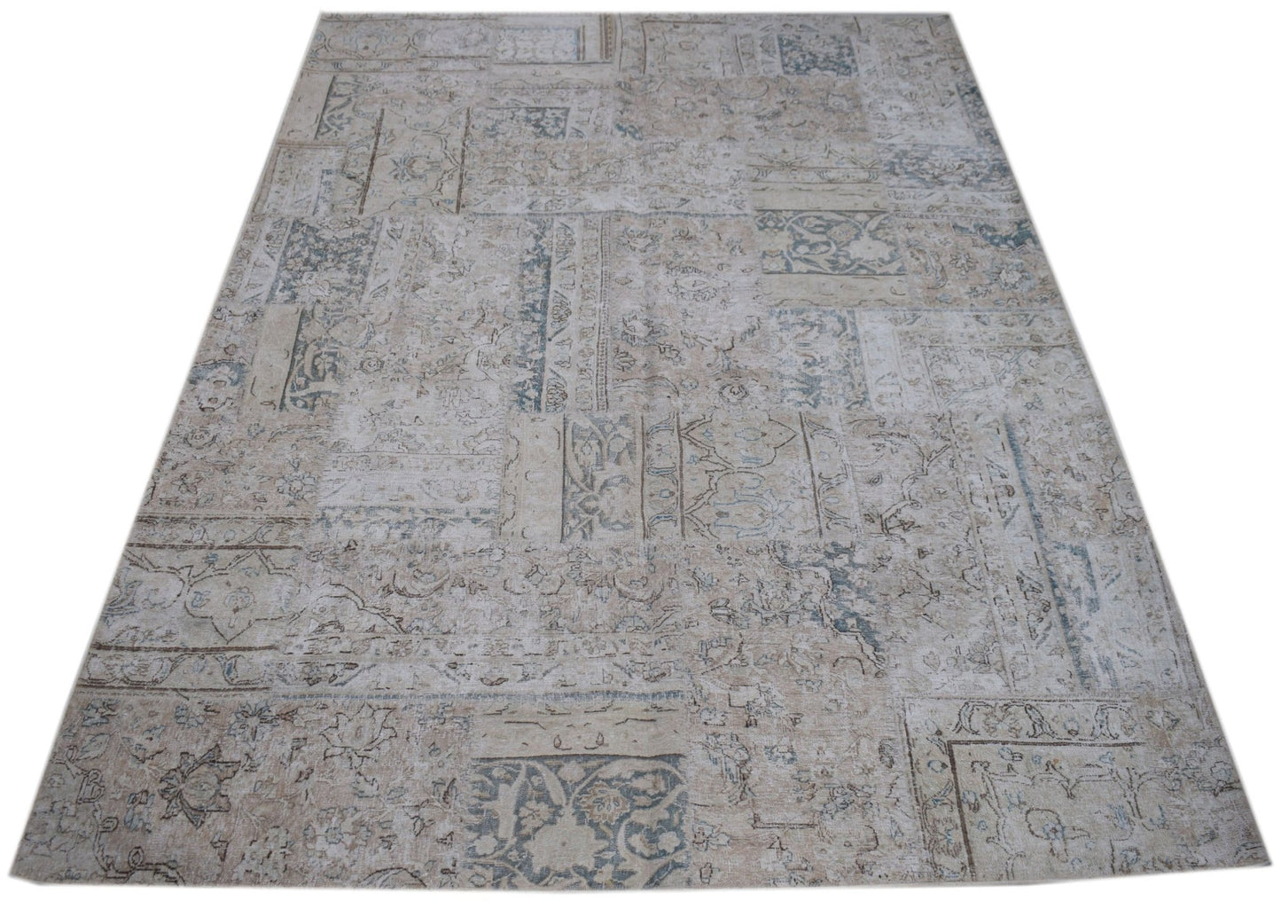 A handmade vintage patchwork rug featuring a faded, neutral-toned pattern of wool on cotton.