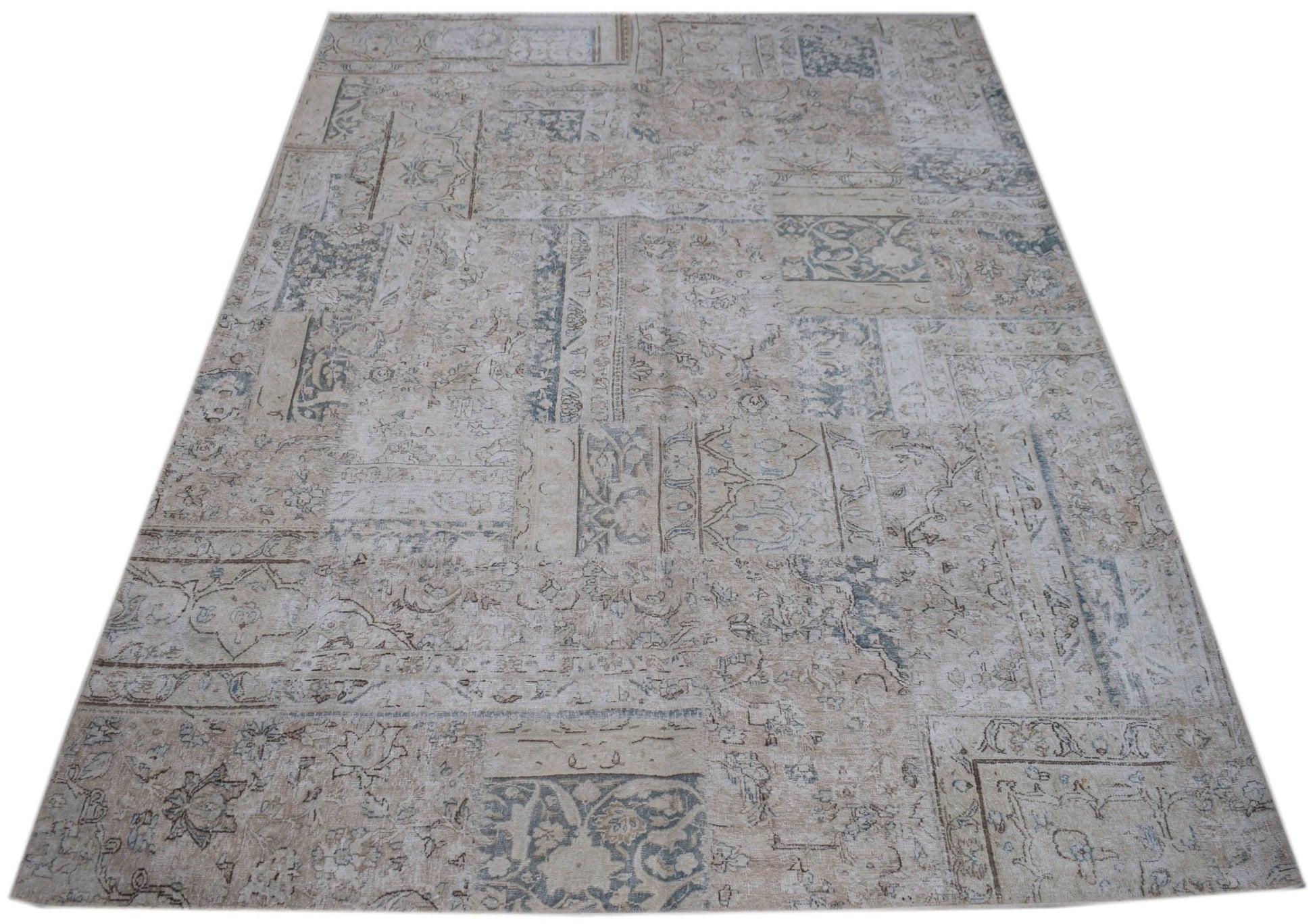 A handmade vintage patchwork rug featuring a faded, neutral-toned pattern of wool on cotton.