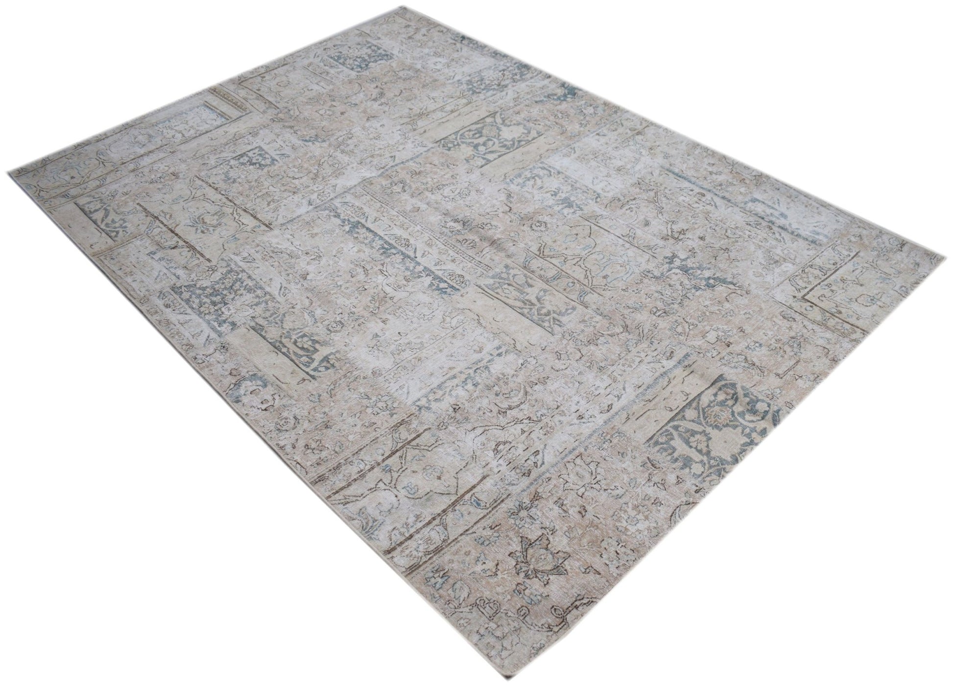 A rectangular handmade rug featuring a vintage patchwork design in muted beige and blue tones.