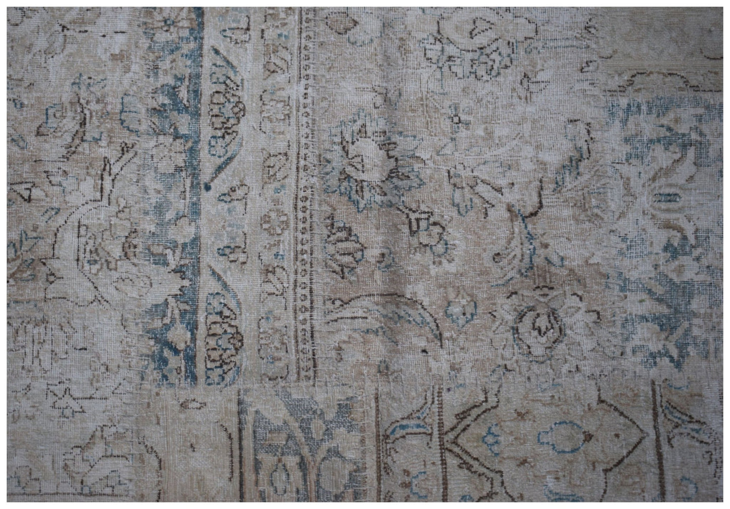 A handmade vintage patchwork rug featuring faded floral patterns in shades of blue and beige.