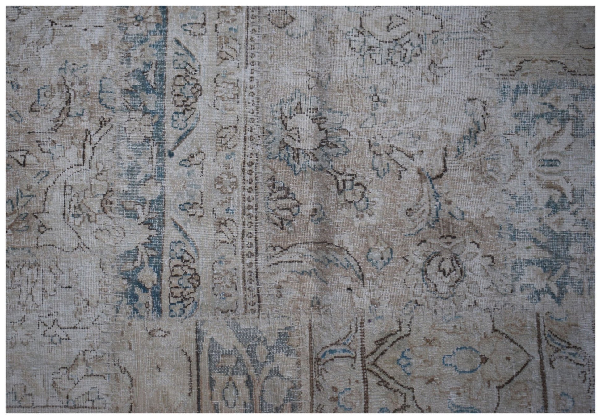 A handmade vintage patchwork rug featuring faded floral patterns in shades of blue and beige.