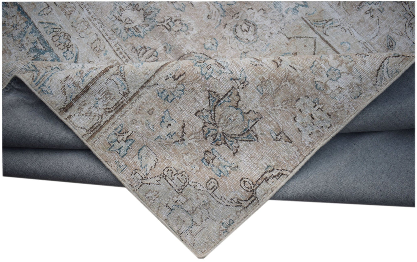 A vintage-style patchwork rug with a faded floral pattern in beige and blue tones.