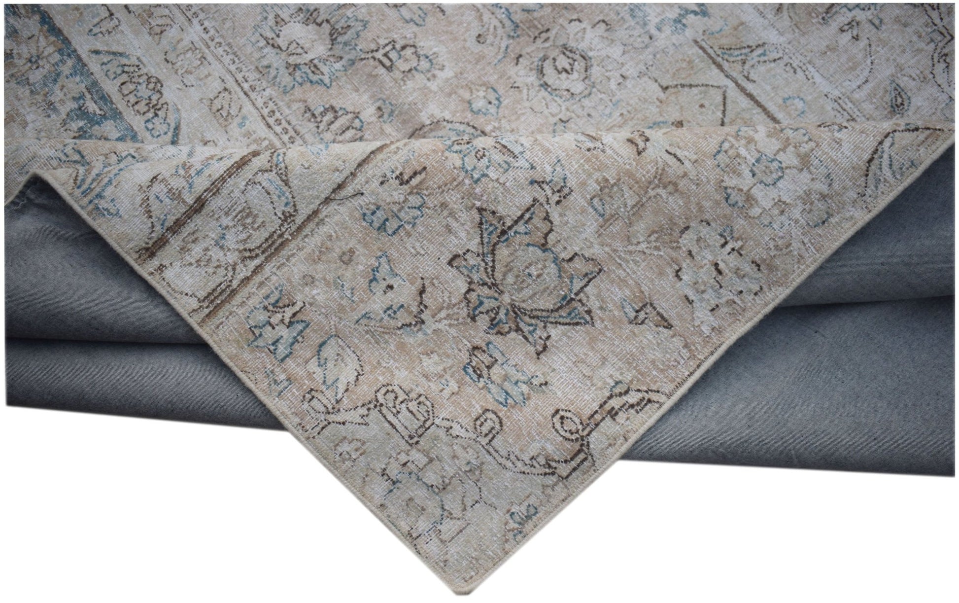 A vintage-style patchwork rug with a faded floral pattern in beige and blue tones.