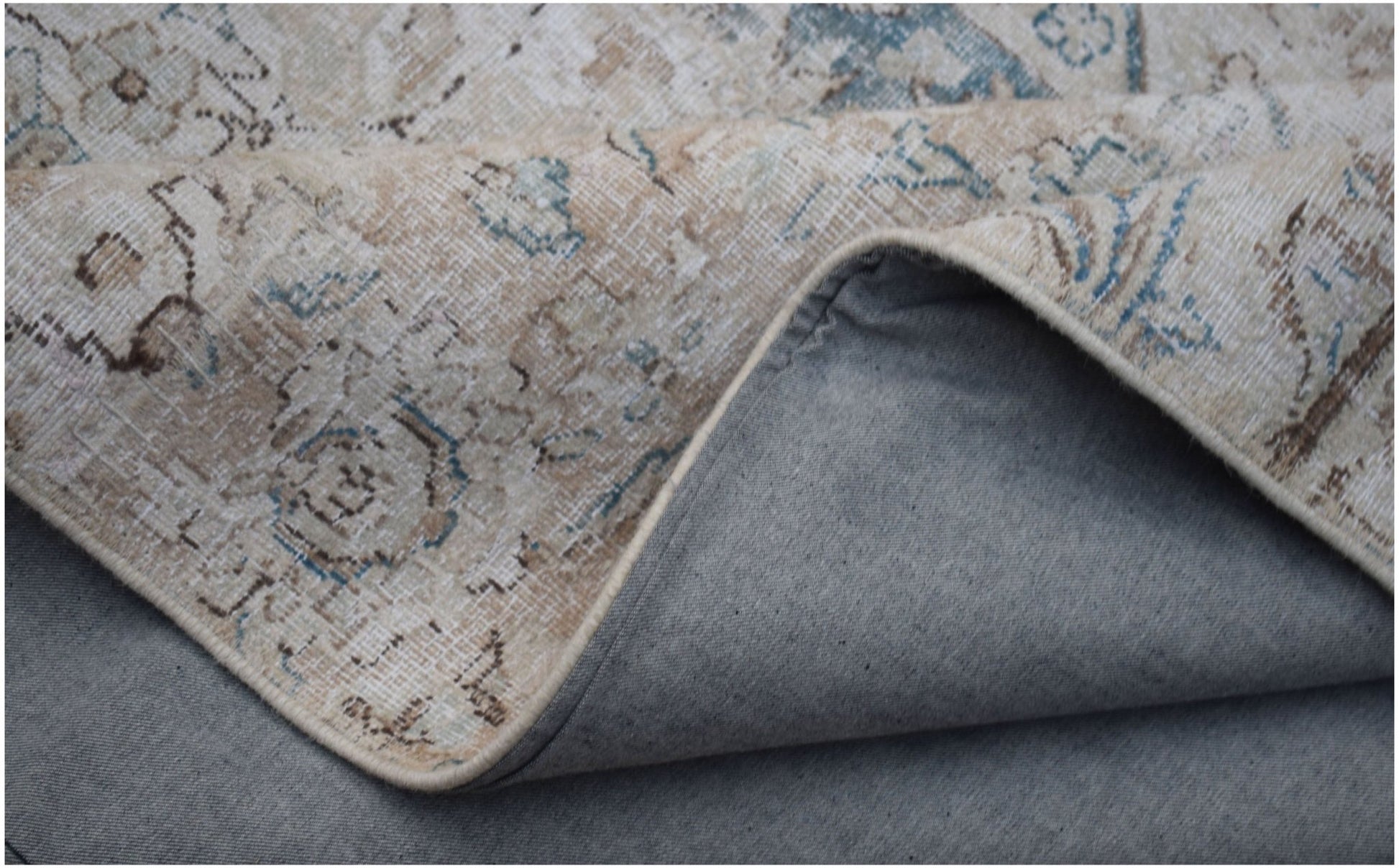 A vintage-style patchwork rug with a faded floral pattern in beige and blue tones.