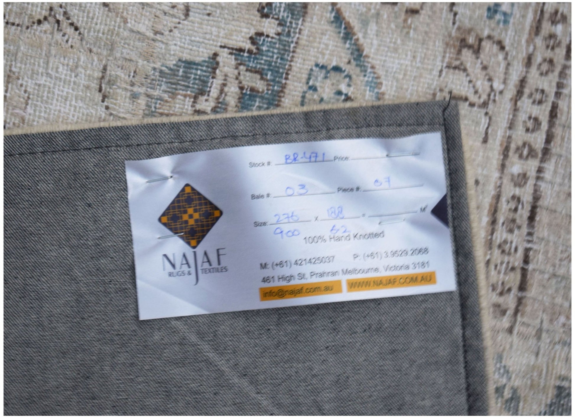 A vintage patchwork rug with a detailed pattern, shown from the back with a product label attached.