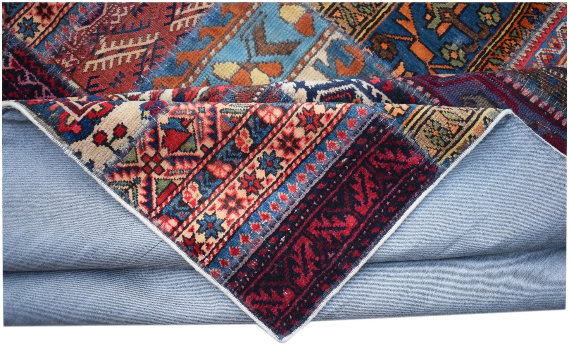 A vintage patchwork rug with intricate geometric patterns in red, blue, and orange wool.