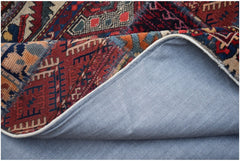 A vintage patchwork rug with a blue fabric backing folded over to show the handmade wool design.