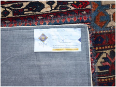 The underside of a vintage patchwork rug showing a product label on a grey fabric backing.