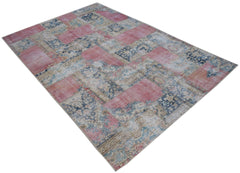 A rectangular vintage patchwork rug featuring a faded floral pattern in shades of pink and blue.