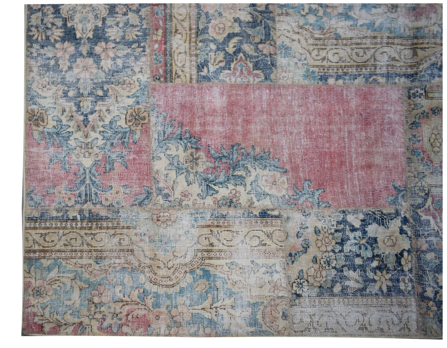 A handmade vintage patchwork rug featuring a mix of floral patterns in blue, pink, and beige tones.