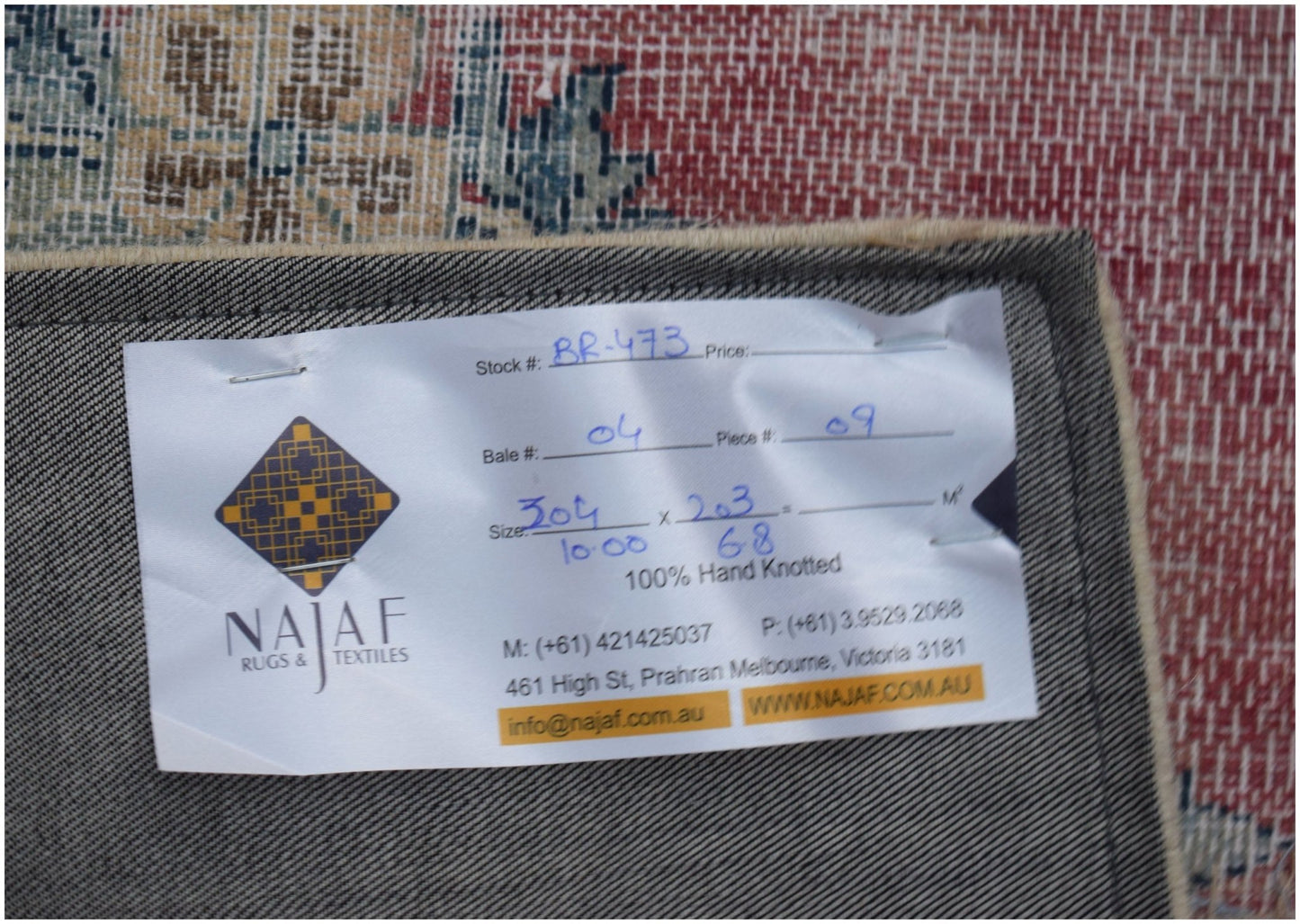 A vintage patchwork rug with a hand-knotted wool construction and a detailed label on the back.