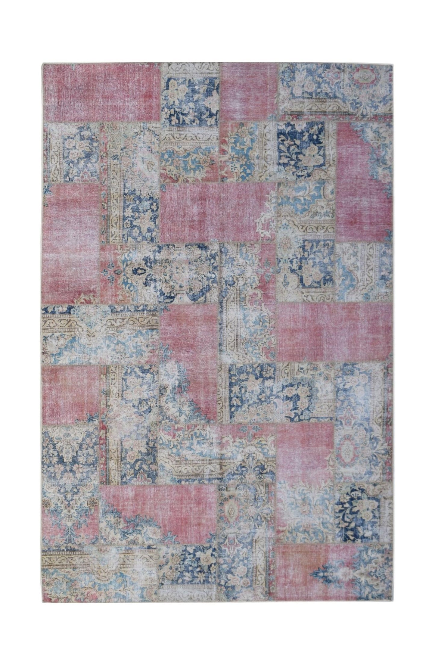 A rectangular handmade patchwork rug featuring a vintage design in shades of pink, blue, and cream.