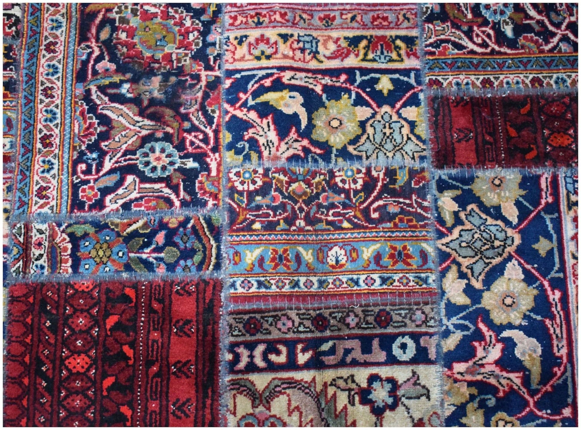 A handmade patchwork rug featuring a variety of vintage floral and geometric patterns in wool.