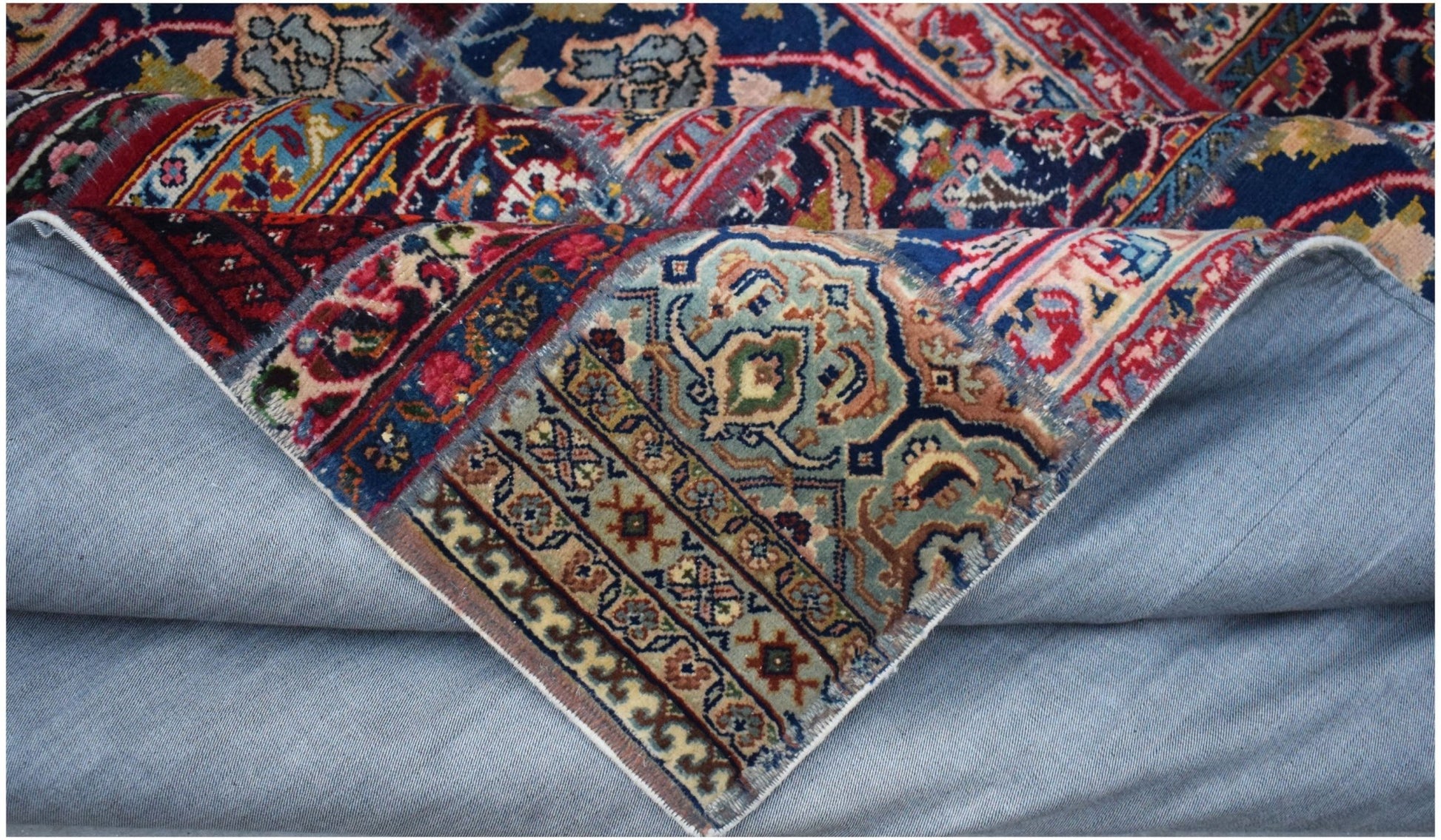 A vintage patchwork rug with intricate floral patterns in blue, red, and beige wool on cotton.