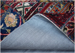 A vintage patchwork rug with a blue denim backing folded to reveal colorful wool patterns.