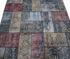 A handmade vintage patchwork rug featuring a variety of ornate floral patterns in red and blue.