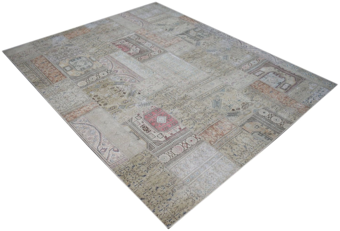 A handmade vintage patchwork rug featuring a faded, multi-patterned design in neutral tones.