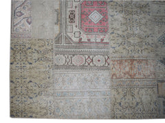 A handmade vintage patchwork rug featuring a mix of faded floral and geometric patterns in wool.