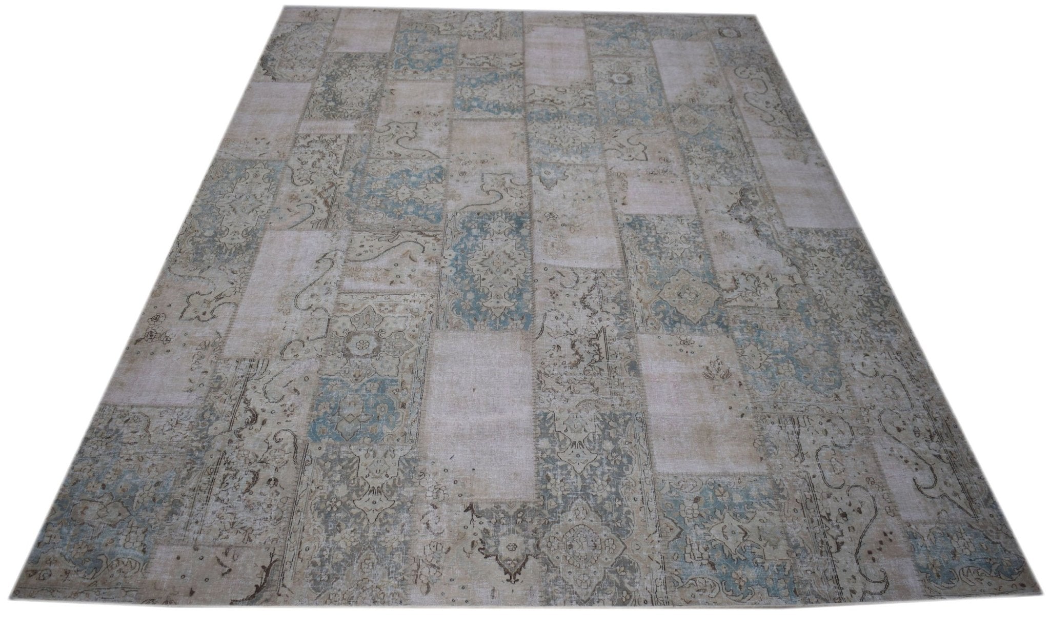 A handmade vintage patchwork rug featuring a faded blue and beige floral pattern.
