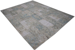 A rectangular handmade patchwork rug featuring a faded vintage design in shades of blue and beige.