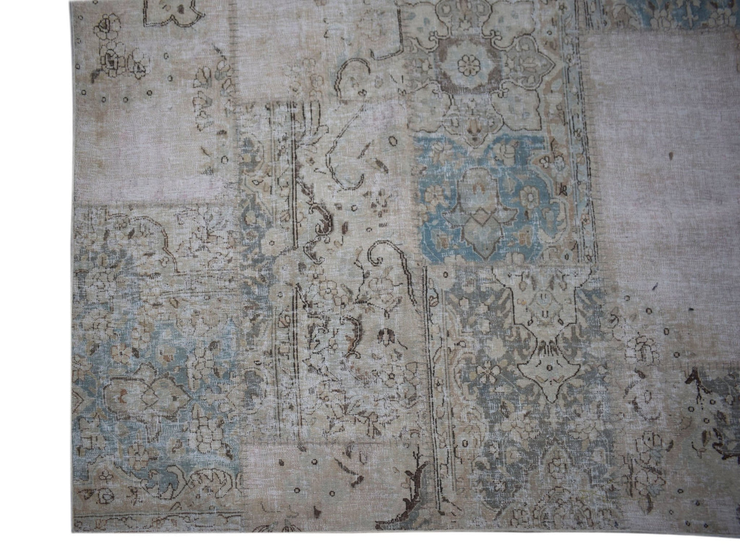A handmade vintage patchwork rug featuring faded floral patterns in shades of blue and beige.