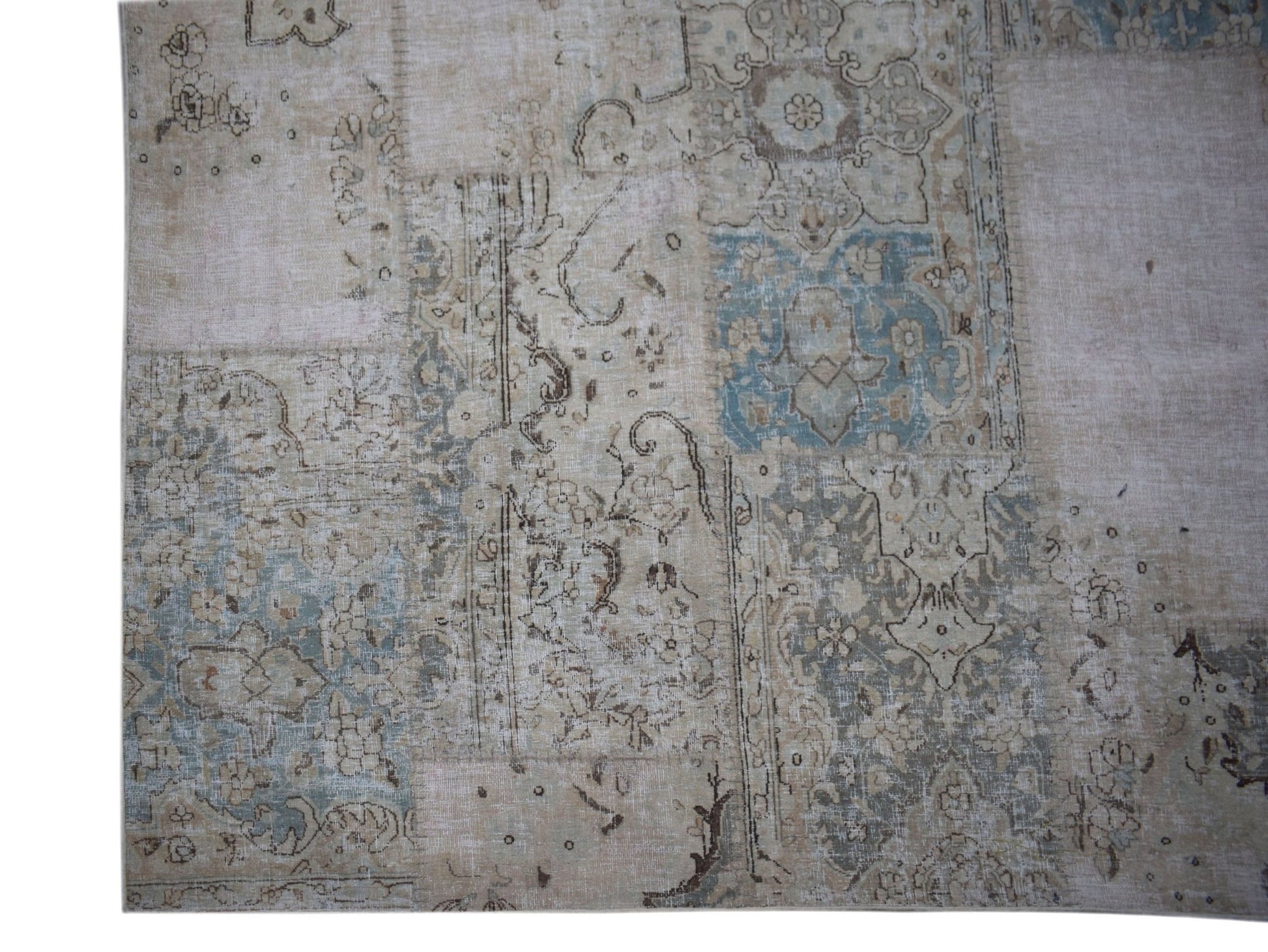 A handmade vintage patchwork rug featuring faded floral patterns in shades of blue and beige.