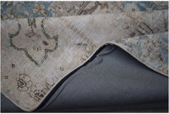 A corner of a vintage patchwork rug with a floral pattern folded to reveal its grey fabric backing.