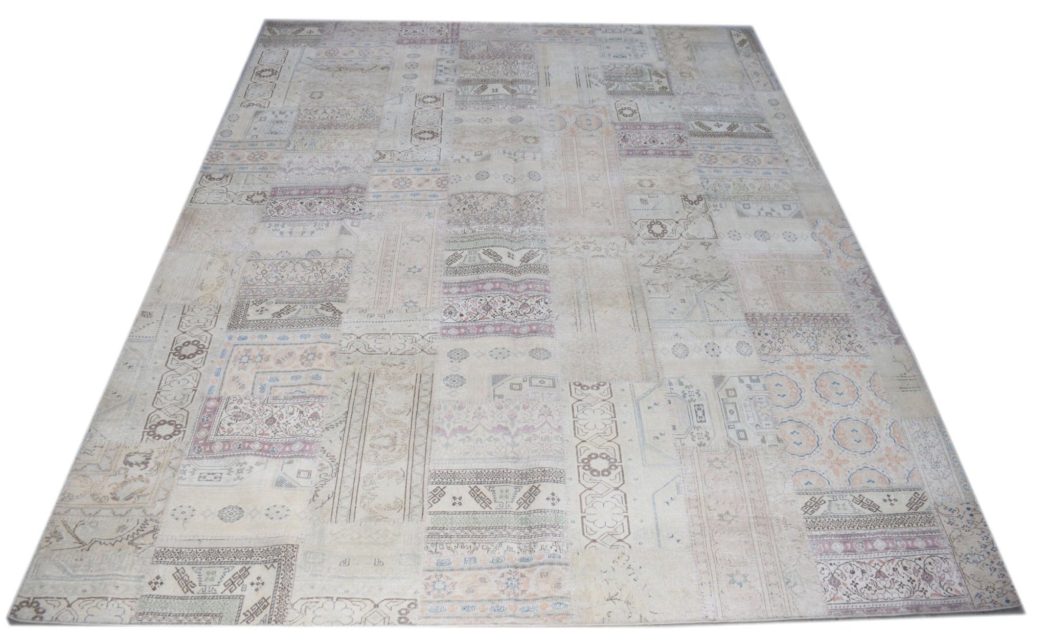 A handmade vintage patchwork rug featuring a neutral color palette with faded traditional patterns.