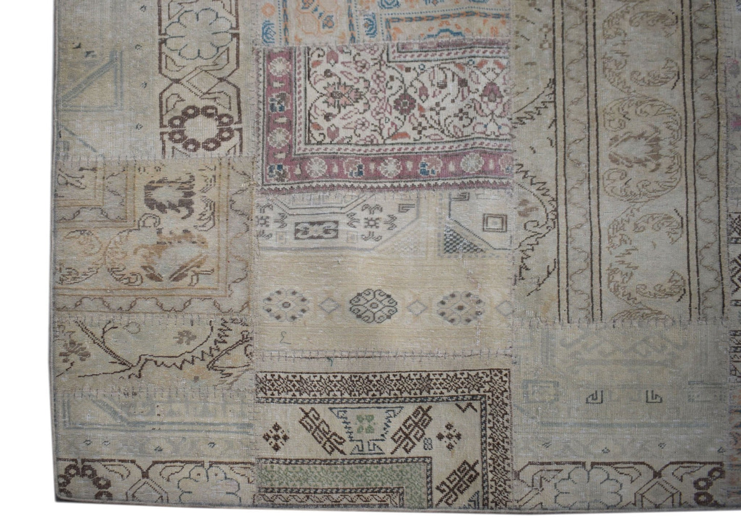 A handmade vintage patchwork rug featuring a neutral color palette and diverse geometric patterns.