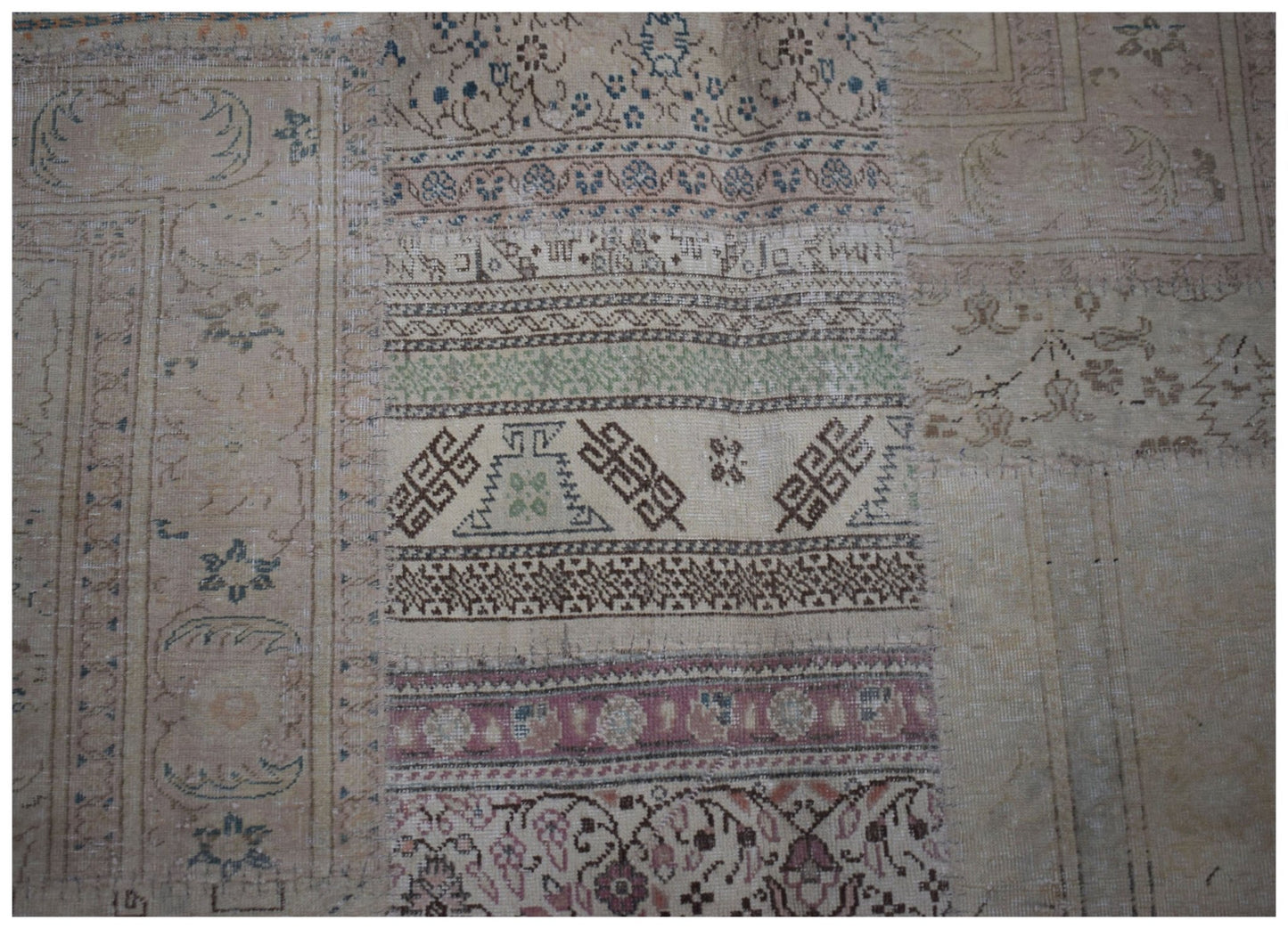 A handmade vintage patchwork rug featuring a variety of intricate geometric and floral patterns.