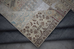A vintage patchwork rug with floral and geometric patterns in muted earth tones.