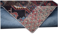 A vintage patchwork runner with a folded corner revealing its wool and cotton construction.