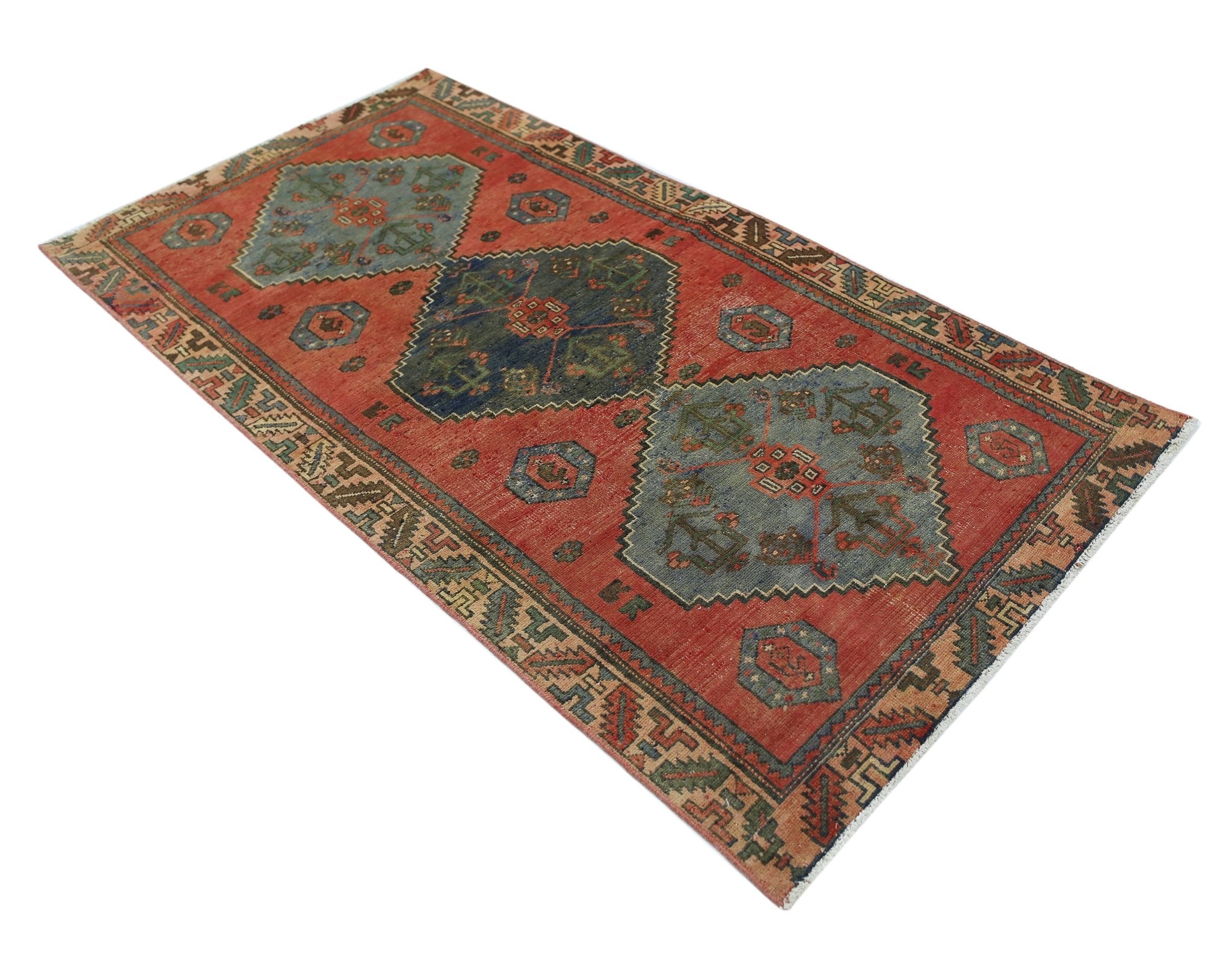 A vintage Persian Afshar rug featuring geometric medallions in blue and green on a red field.