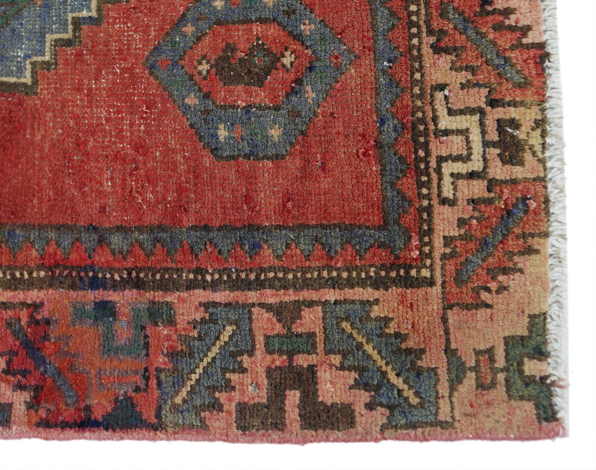 A close-up of a vintage Persian Afshar rug featuring geometric patterns in red, blue, and tan.