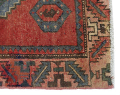 A close-up of a vintage Persian Afshar rug featuring geometric patterns in red, blue, and tan.
