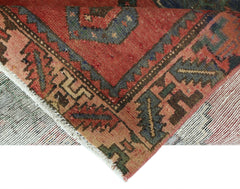A corner view of a vintage handmade Persian Afshar rug featuring geometric patterns in red and blue.